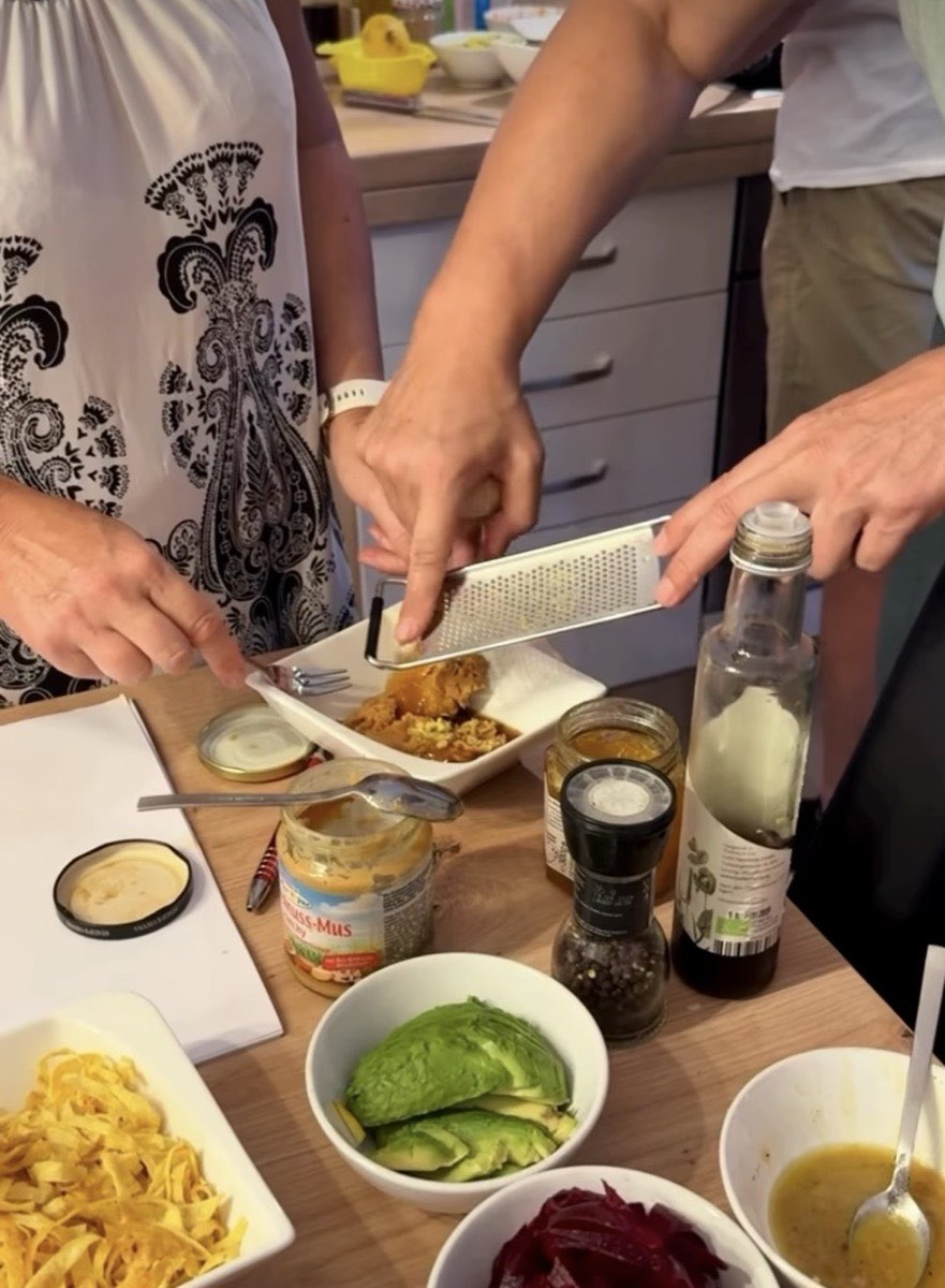 Beim Kochworkshop wird eine Zutat über eine Schale gerieben, daneben Gewürze, Öl und Avocado
