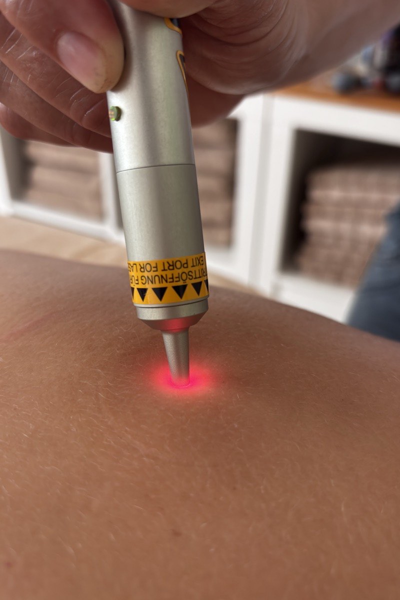 Laserakupunktur: das Handgerät setzt einen roten Lichtpunkt auf die Haut